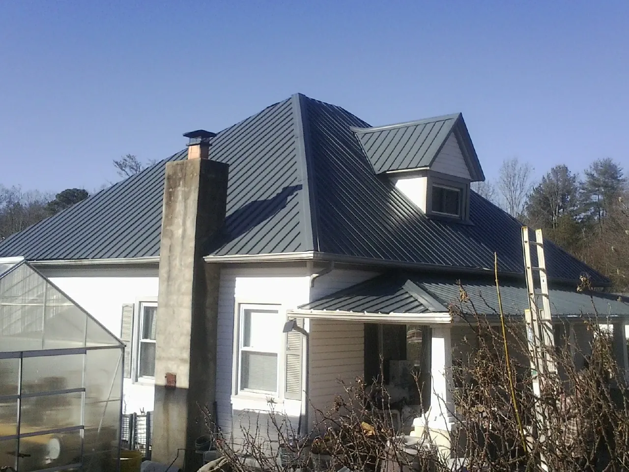 Dark blue standing seam metal roof on a white farmhouse with dormer — Slate & Tile Roof Repair by Roofing Brothers in Moroni