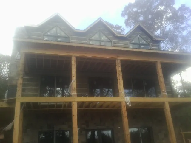 Dormers and porch framing on a large log home under construction — Roof Coating work by our crew in Moroni