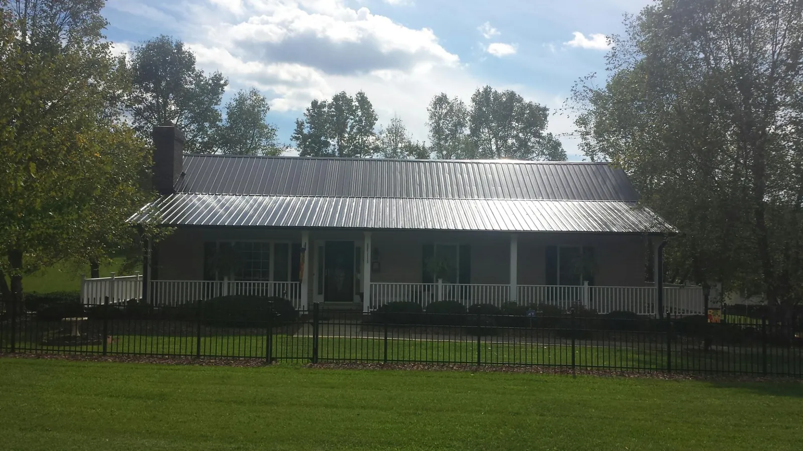 Gray metal roof on a brick ranch with a full width front porch — Gutter Guard Installation work by our crew in Moroni