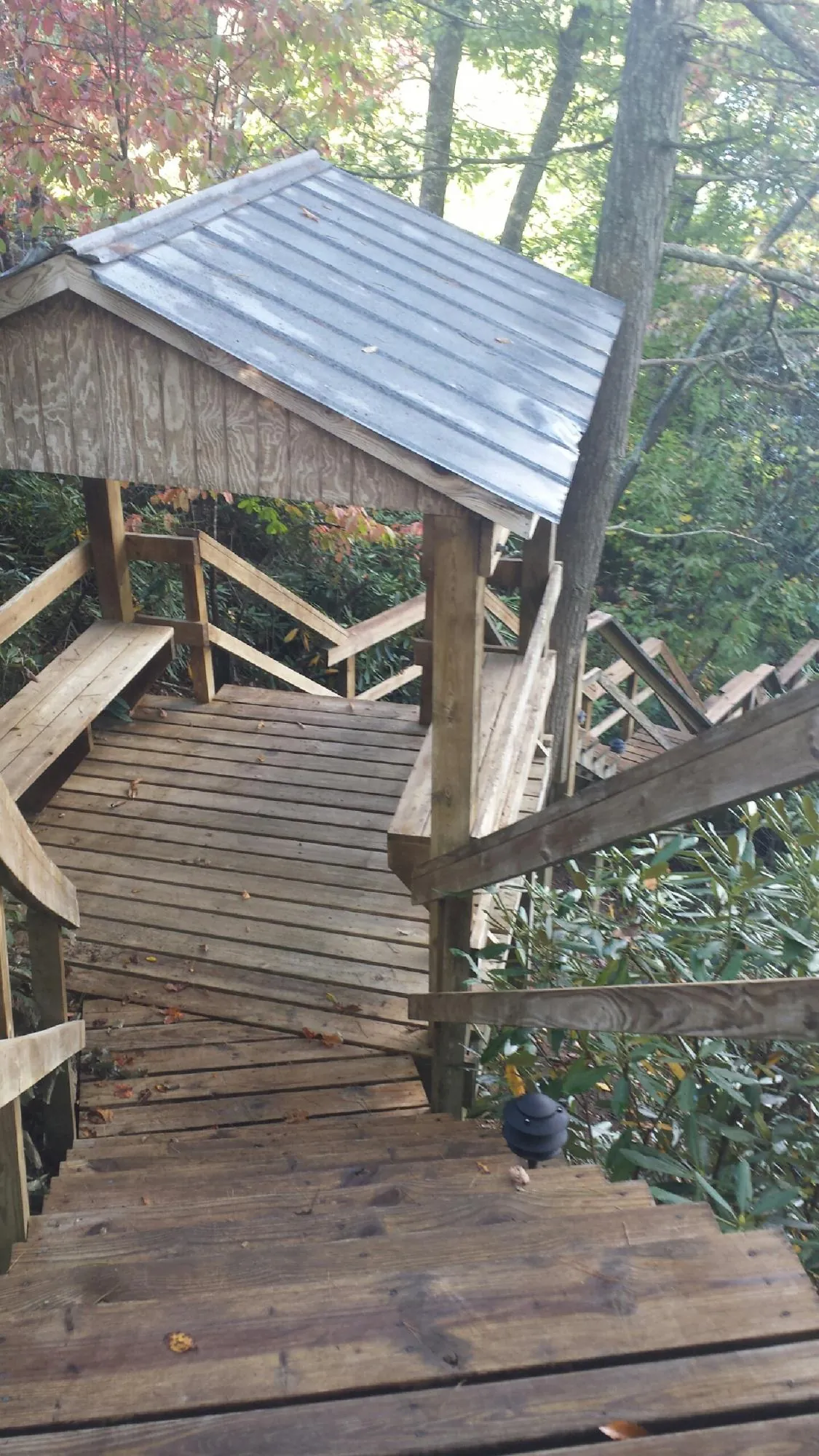 Metal roofed shelter over wooden steps on a wooded walkway — Skylight Repair & Installation work by our crew in Moroni