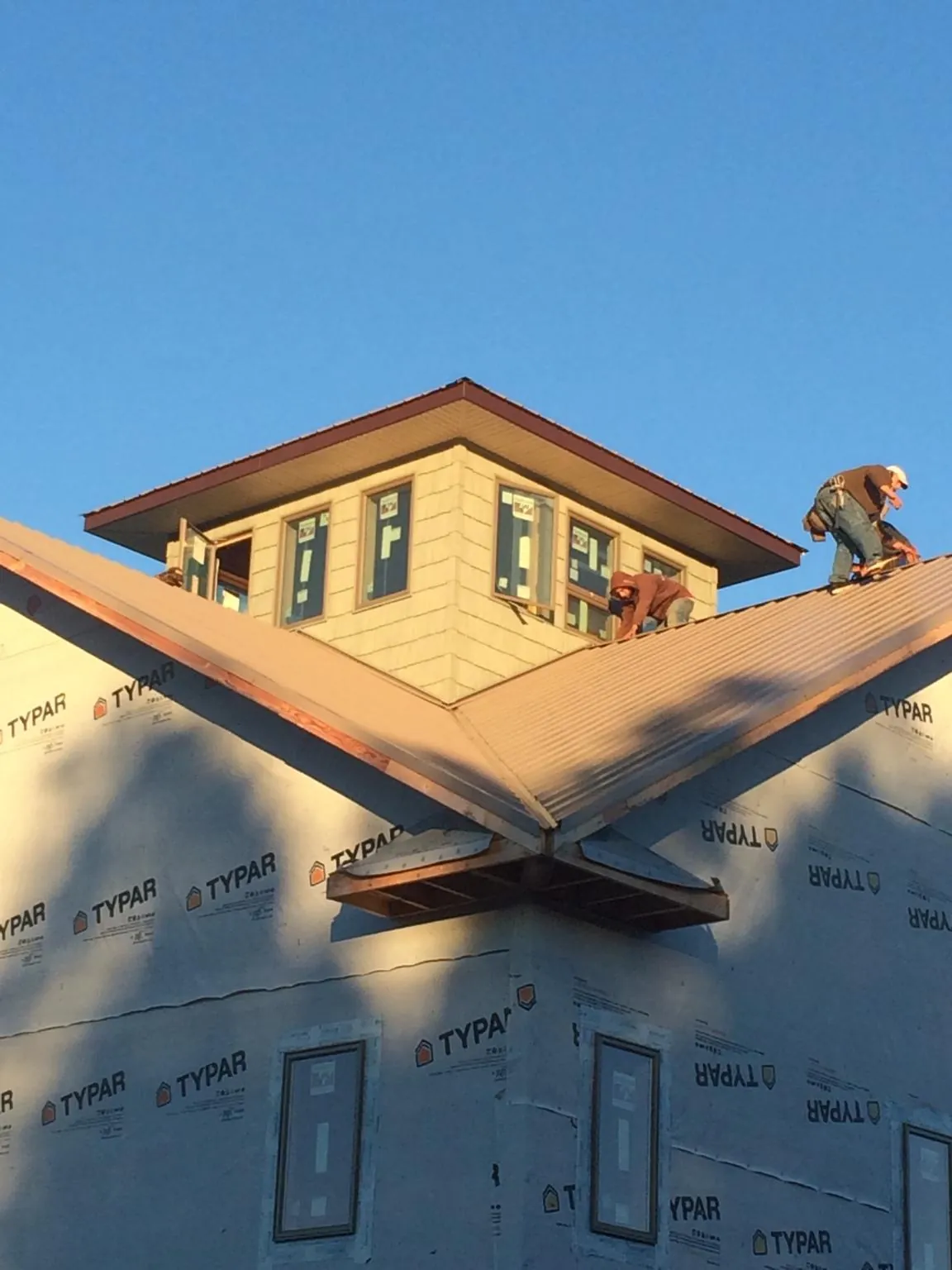 Roofers working around a rooftop cupola on a new metal roof at sunset — Roof Waterproofing in Moroni by Roofing Brothers